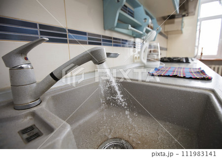 In the kitchen, water flows from a faucet into the sink. 111983141