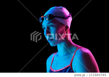 Portrait of skilled, young woman swimmer with water droplets on skin, show intricate in vibrant neon light against black studio background. Portrait of skilled, young woman swimmer with water droplets on skin, show intricate in vibrant neon light against black studio background. 111983795