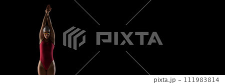 Young, skilled female swimmer in swimwear, goggles and cap against black studio background with negative space to insert text. Young, skilled female swimmer in swimwear, goggles and cap against black studio background with negative space to insert text. 111983814