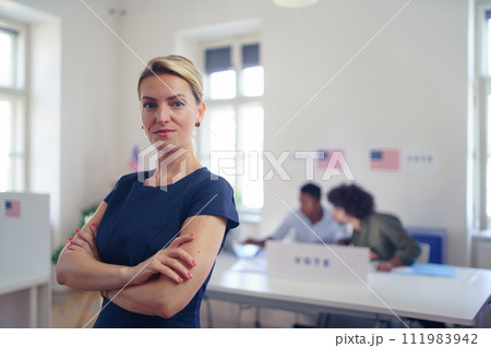 Portrait of female voter filling election ballot paper. US citizen voting in polling place on election day, usa elections. Portrait of female voter filling election ballot paper. US citizen voting in polling place on election day, usa elections. 111983942