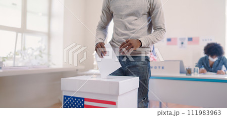 Unrecognizable woman putting her vote in the ballot box, usa elections. Banner with copy space. 111983963