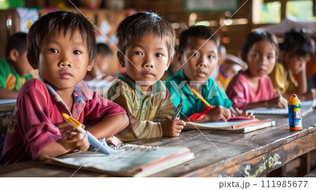 Group of happy asian kids students sitting in classroom and writing in notebooks 111985677
