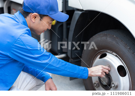 タイヤの運行前確認を行うトラックドライバー 111986011