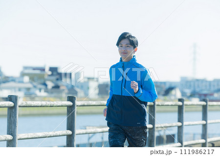 河川敷をランニングする若い男性 111986217