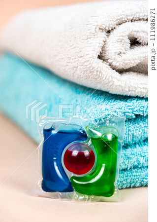Laundry pod on beige background with soft towels Laundry pod on beige background with soft towels 111986271