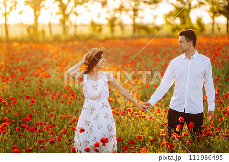 Loving couple in the poppy field at sunset. Enjoying time together. love and lifestyle. 111986495