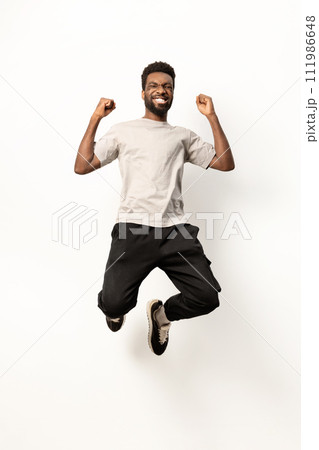 Joyful African American Man Jumping with Excitement in Studio 111986648