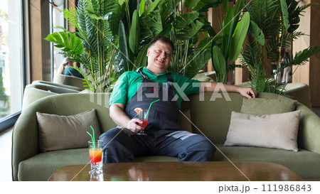 Portrait of an adult man in work clothes drinking a cocktail at lunch while sitting in a cool room 111986843
