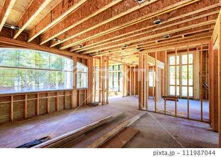 New home is being built at building area with unfinished framing beams wooden home in construction phase New home is being built at building area with unfinished framing beams wooden home in construction phase 111987044