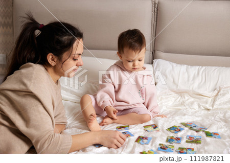 pretty mother playing puzzle together with her little child girl in bedroom 111987821