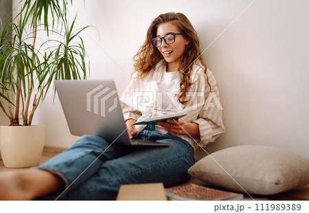Young woman sits at home, learning preparing for exam using literature laptop, concept of knowledge. Young woman sits at home, learning preparing for exam using literature laptop, concept of knowledge. 111989389