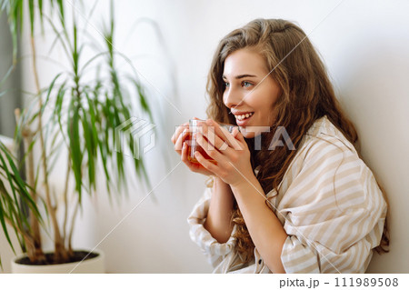 Happy woman drinks hot drink and sits on phone, reads book, flips through magazine. Vacation concept 111989508