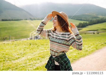 Happy female traveler exploring area in green valley with mountains in background. Concept of nature 111990115