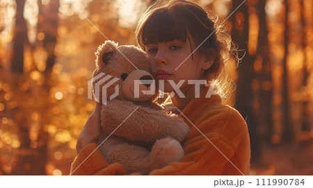 Beautiful young woman with teddy bear in the autumn forest. 111990784