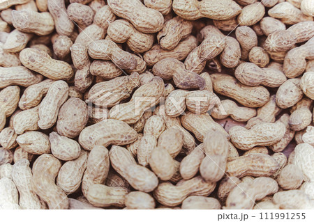 Raw unpeeled groundnuts on brown surface background for food Raw unpeeled groundnuts on brown surface background for food 111991255