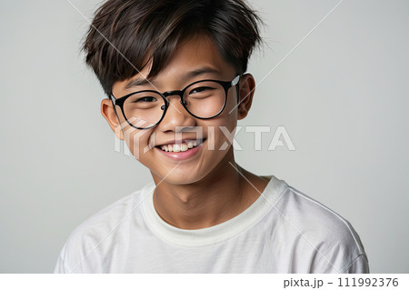 happy darkskinned schoolgirl teenager wearing eyeglasses on a gray solid background with copy space.  AI generated 111992376