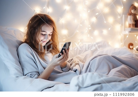 AI-generated content. A teenage girl sits in bed in a bedroom decorated with Christmas decor and looks at a mobile phone or tablet. 111992806