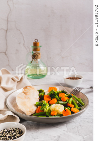 Mixed vegetables and steamed chicken breast on a plate on the table vertical view 111993762
