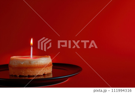 a birthday cake and candle, with a birthday message on a red background, light red and crimson 111994316