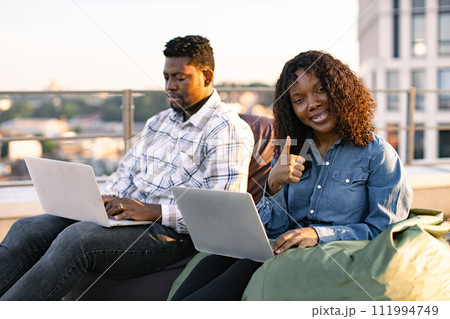 African colleagues working with laptops while sitting at beanbags. African colleagues working with laptops while sitting at beanbags. 111994749