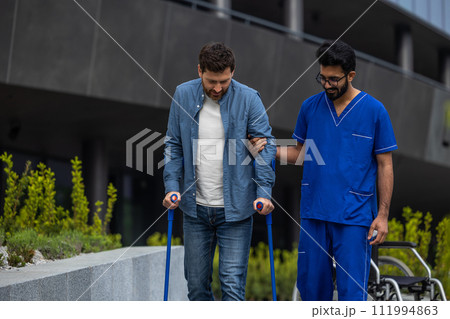 Man with sticks walking with a male nurse 111994863