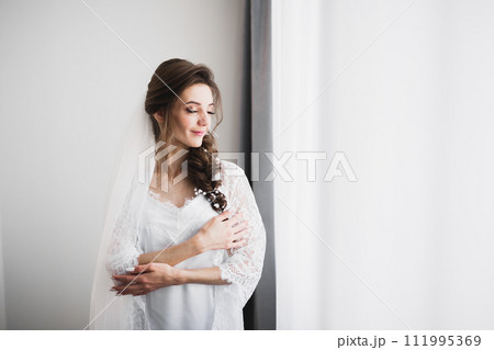 Luxury bride in white dress posing while preparing for the wedding ceremony Luxury bride in white dress posing while preparing for the wedding ceremony 111995369