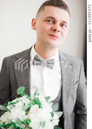 Beautiful man, groom holding big and beautiful wedding bouquet with flowers 111995372