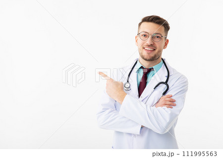 Portrait of confident young medical doctor on white background. Doctor points to to copy space Portrait of confident young medical doctor on white background. Doctor points to to copy space 111995563