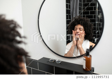 Brunette curly-haired man having morning procedures in the bathroom Brunette curly-haired man having morning procedures in the bathroom 111995731