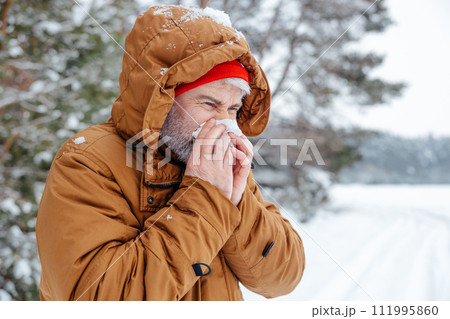 Man in a winter forest looking sick and unwell 111995860
