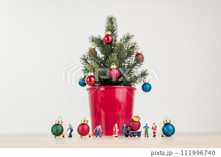 Miniature people decorating giant Christmas tree 111996740