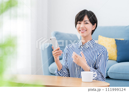 リビングでスマホを操作する女性。 111999124