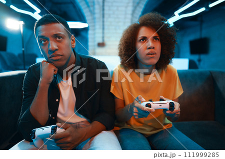 Man and woman play console and show emotions. 111999285