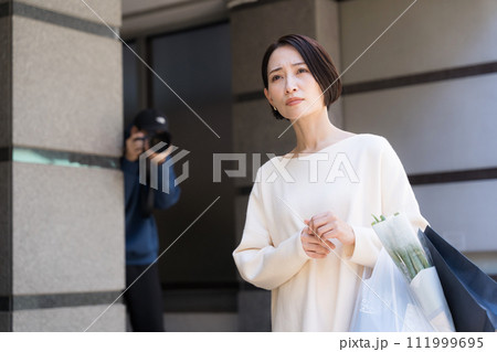 建物に隠れて女性の写真を撮る人 111999695