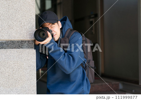 建物に隠れて写真を撮る人 111999877