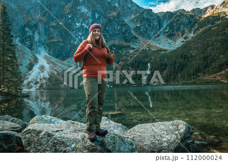 Shot of woman traveler relaxing alone travel in adventure vacation with backpack enjoying standing on the top of the mountain near Famous mountains lake Morskie oko or sea eye lake In High Tatras 112000024