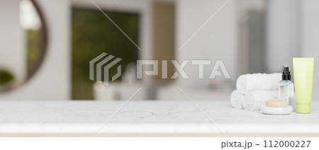 Toiletries and a copy space for display product on a white marble tabletop in a modern bathroom. 112000227