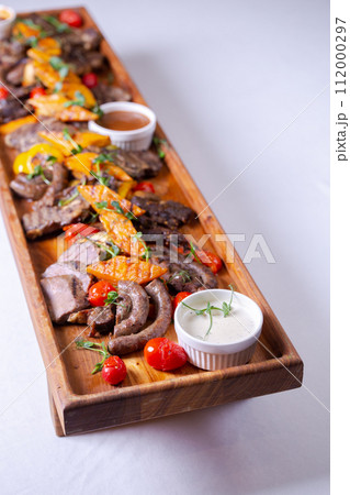 Rustic wooden platter with assorted meats and vegetables Rustic wooden platter with assorted meats and vegetables 112000297