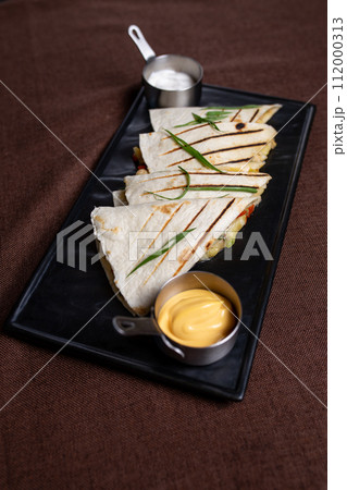 top view of quesadilla with grilled chicken and cheese with vegetables, sour cream, salsa 112000313