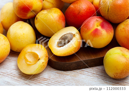 Whole and halved ripe apricots on wooden background Whole and halved ripe apricots on wooden background 112000333