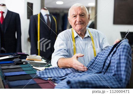 Male tailor demonstrating of fashionable suit in apparel shop Male tailor demonstrating of fashionable suit in apparel shop 112000471
