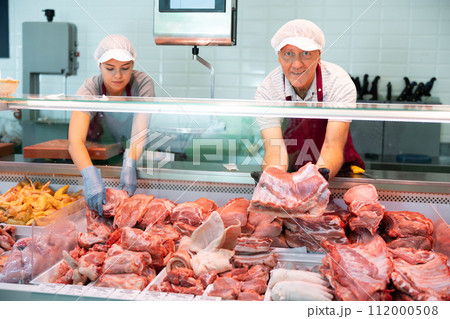 Sales assistant man shows ribbon damp gammon of bacon in meat store Sales assistant man shows ribbon damp gammon of bacon in meat store 112000508