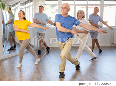 Elderly man learning dynamic dances at group choreography lesson 112000571
