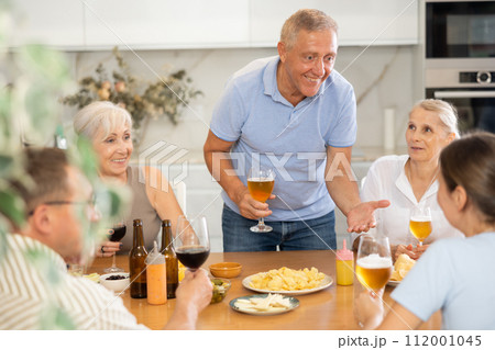 Old men and women talking merrily while having snack in the kitchen 112001045