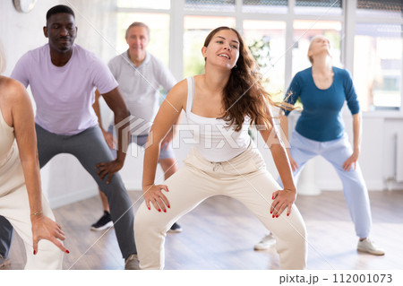 Young woman teaching hip hop to group of multiethnic mature people 112001073