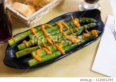 Steamed asparagus under romesk sauce on a black plate 112001244