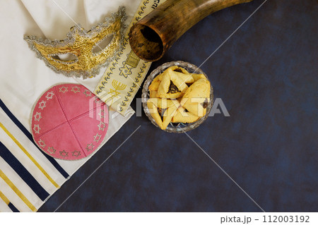 Celebration of Jewish Purim holiday with hamantaschen, Hamans ears cookies, carnival mask, noisemakers 112003192