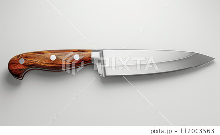 A chef's knife with a reflective blade and a finely crafted wooden handle is presented on a light background, highlighting its sleek design and sharpness. 112003563