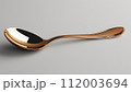 A single copper spoon with a reflective surface on a neutral grey background. 112003694