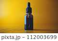 A single amber dropper bottle against a vibrant yellow background, showcasing a minimalist aesthetic. 112003699